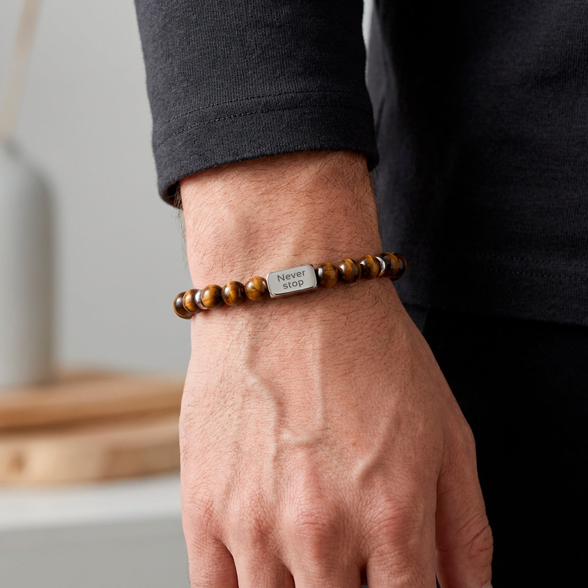 Ruskea tiikerinsilmä rannekoru miehen kädessä