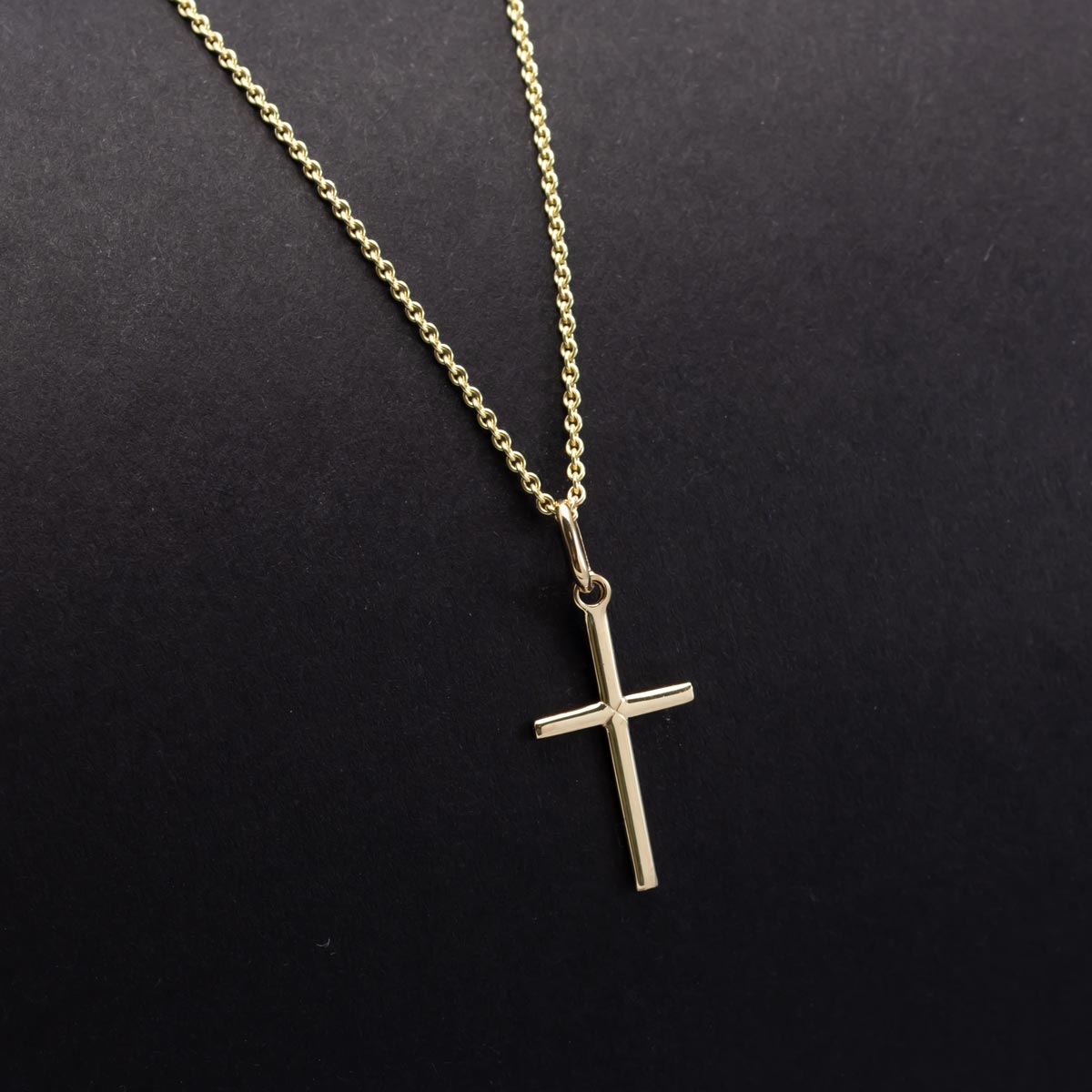 Small gold cross pendant on a dark background, IBBLK216