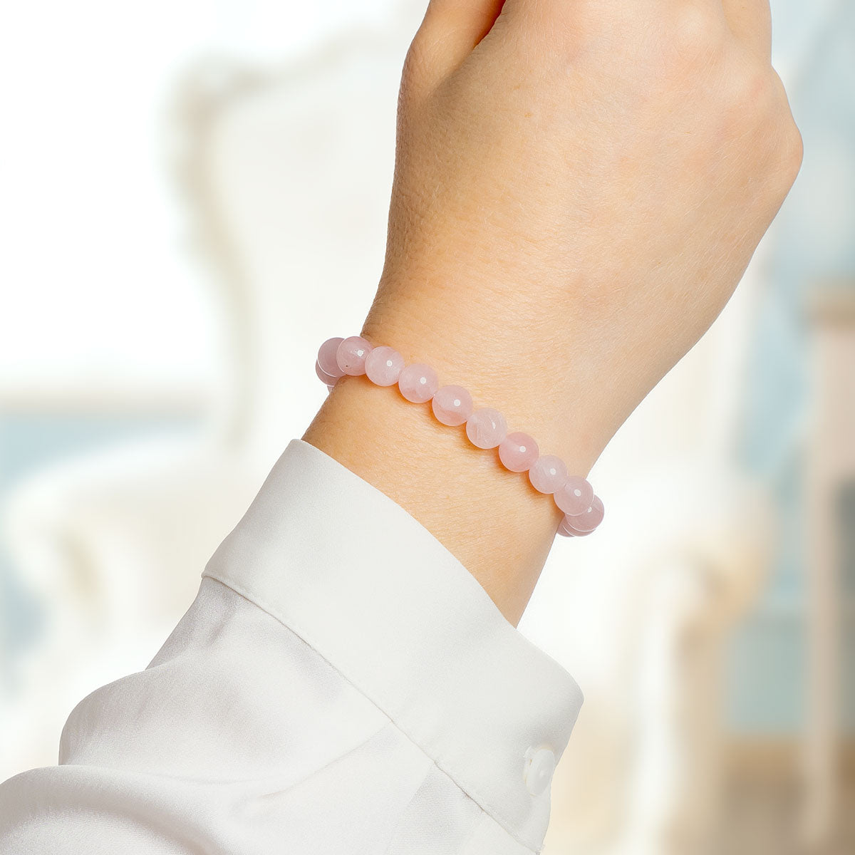 Ruusukvartsi korukivi rannekoru naisen kädessä