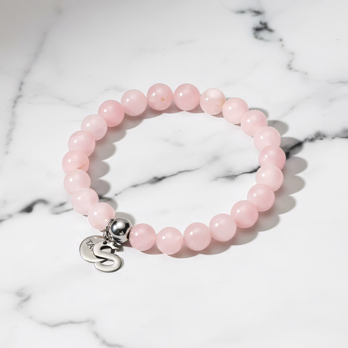 Vaaleanpunainen ruusukvartsi rannekoru pöydällä | Taika-korut