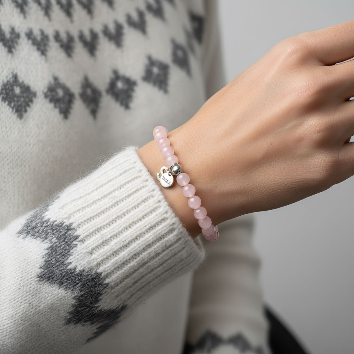 Vaaleanpunainen ruusukvartsi rannekoru naisen kädessä | Taika-korut